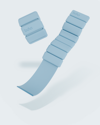 Light blue Vibrant Bangles Set for an Energizing Look features soft, rectangular weights on a flexible band. One weight floats separately, highlighting the modular design against a clean white background, emphasizing its sleek appearance.