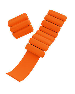 Vibrant orange weighted wrist and ankle bands from the "Vibrant Bangles Set for an Energizing Look" feature cushioned rectangular segments, adjustable straps, five segments per band, and "bala" branding on two segments. One band is closed while the other is open. Perfect for fitness workouts.