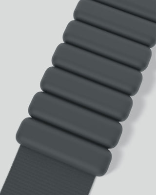 Close-up of a dark green, segmented oblong-link watch strap with a textured band against a soft pale gray backdrop, emphasizing its smooth matte finish.