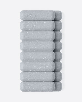 A vertical stack of grey, rectangular weights with rounded edges on a white surface features a speckled texture and the word "bala" imprinted on the top weight, visually contrasting the Vibrant Bangles Set for an Energizing Look.