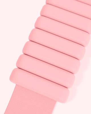 Close-up of a pink watch strap from the Vibrant Bangles Set, featuring smoothly curved rectangular segments in a linear arrangement connected by a flexible band. The soft off-white background accentuates the strap's pastel hue.