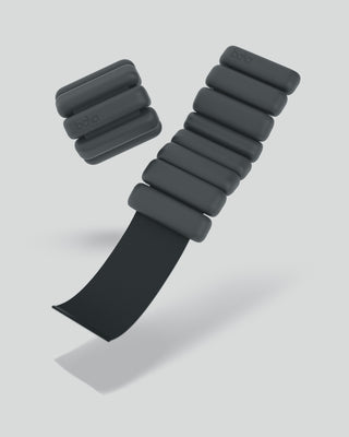 Bala's Vibrant Bangles Set is showcased against a light backdrop, with one fully visible weight featuring six cylindrical segments on a black strap, while another similar weight appears partially cut off beside it.