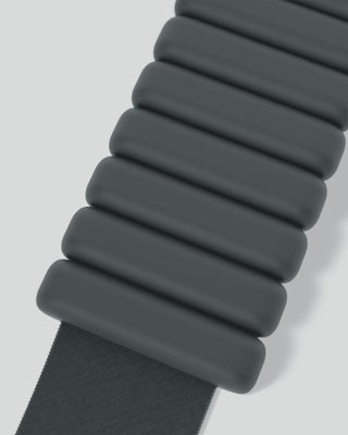 A sleek, dark green segmented watch band with a pill-shaped design is diagonally displayed on a light gray background, showcasing modern minimalism akin to the Vibrant Bangles Set for an Energizing Look.