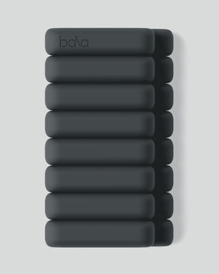 A stack of sleek, dark teal Vibrant Bangles arranged neatly on a light gray background. Each cushioned rectangular weight is designed for fitness, featuring the subtle Bala logo embossed on top. The minimalist design embodies modern aesthetic trends.