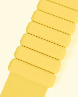 The Vibrant Bangles Set features a yellow strap with vertical, rounded rectangular links, creating a segmented appearance. Displayed on a light yellow background, the strap's vibrant color is enhanced.