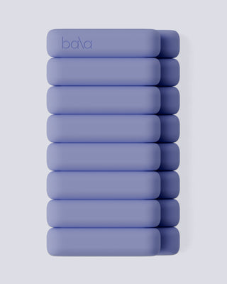 Ten vertically stacked, smooth, lavender weights with rounded edges are set against a gray background. The top weight is embossed with "bala.