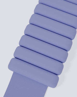 A close-up of the Vibrant Bangles Set features a lavender strap with an accordion-like design. The strap has stacked, raised, rounded rectangular segments, creating a textured look against a light, neutral background.