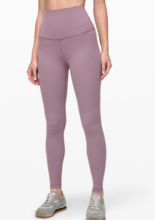 A person in High-Waist Powercore Leggings, Lotus Root Pink, and gray sneakers with white soles stands against a plain white background, hands relaxed by their sides. The leggings feature visible seam lines, and the sneakers have a minimalist design.