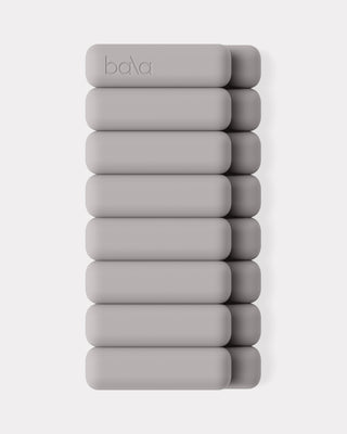 Eight stackable, light gray rectangular weights with rounded corners and "bala" embossed on one, are vertically displayed in two parallel columns of four against a plain white background.