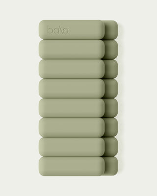 A stack of ten Vibrant Bangles, green and oblong in shape, arranged vertically against a light green background. The bangles have a smooth texture with "bala" embossed on the top bangle.
