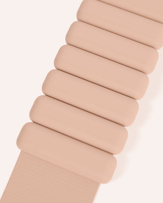 A close-up of a beige segmented wristband from the Vibrant Bangles Set reveals rounded rectangular links, creating a flexible look. Set against a light cream background, it enhances the wristband's modern and minimalistic design.