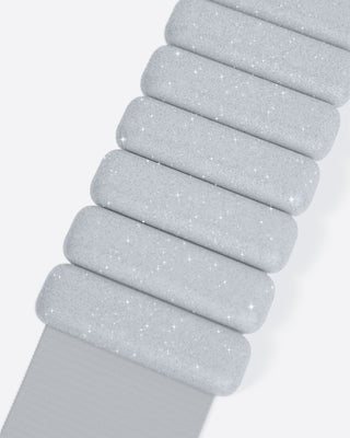 A close-up of the Vibrant Bangles Set reveals a flexible, metallic strap made of textured, rectangular segments with a sparkly silver appearance, set against a plain white background.