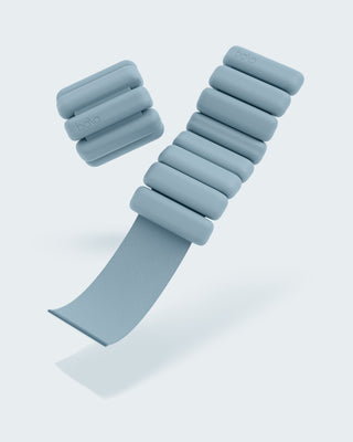 Image of two sea-colored Vibrant Bangles Set on a light background. One is fully closed with six rounded, evenly spaced segments, and the other is open, showing a gray strap for adjustable fitting. The word "bala" is printed on one segment.